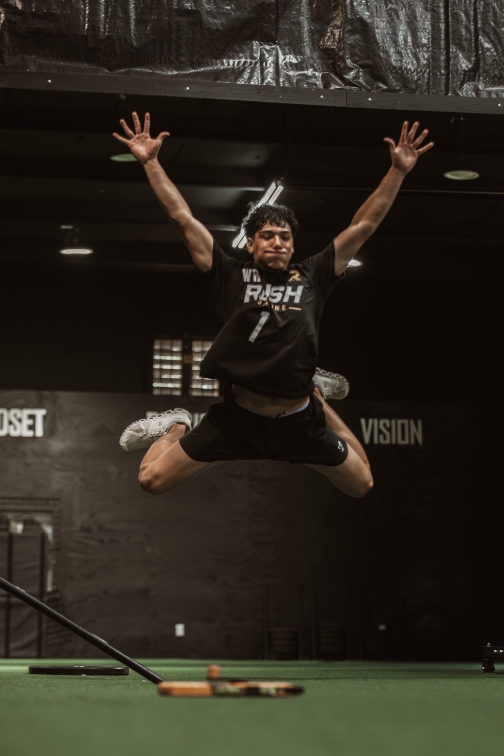 Athlete jumping with arms raised in front of the Vision wall at Rush Combine