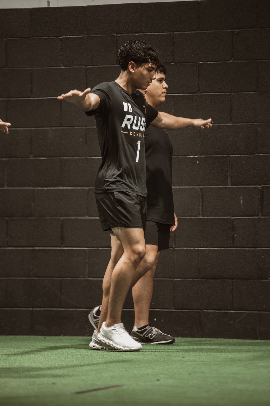 Two athletes stretching side by side at Rush Combine